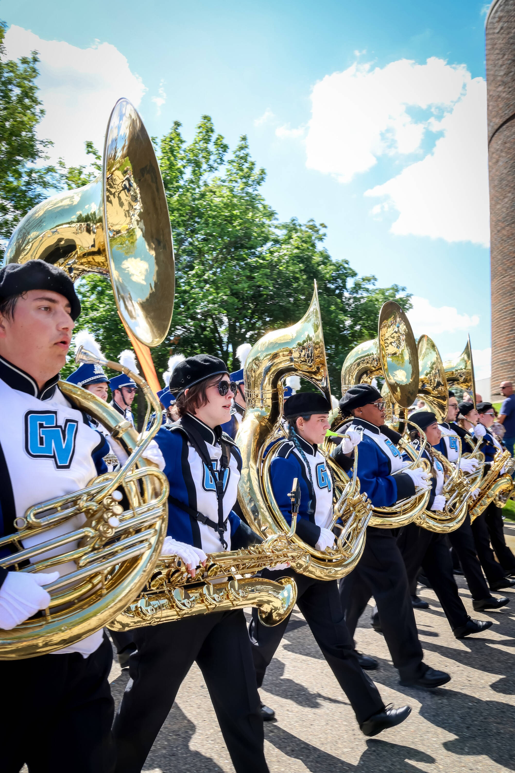 sousas and a bari sax player in line marching the parade route to lubbers stadium